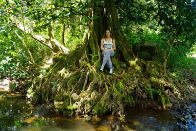 Portrait of woman sitting on tree in forest