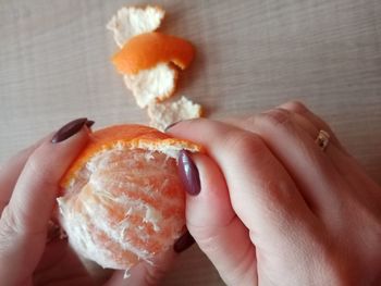 A human hand peeling an orange fruit.