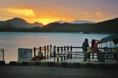 People on sea against sky during sunset