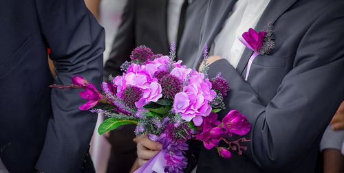 Midsection of man holding flower bouquet