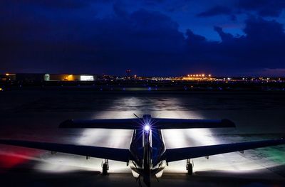 Illuminated airport runway against sky at night