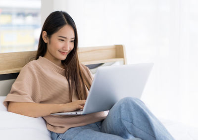 Young woman using phone while sitting on sofa