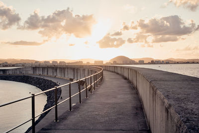 Bridge over sea against sky during sunset