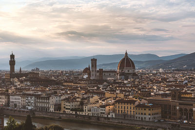 High angle view of city buildings against cloudy sky