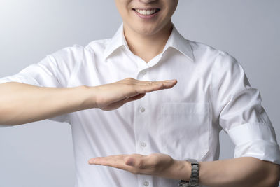 Midsection of smiling young woman standing against white background