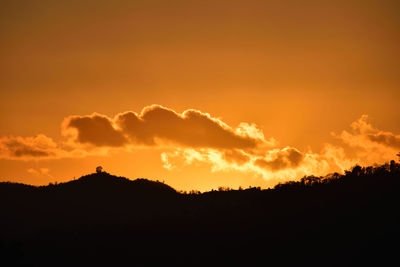 Low angle view of silhouette landscape against orange sky