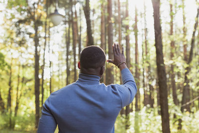 Rear view of man gesturing in forest