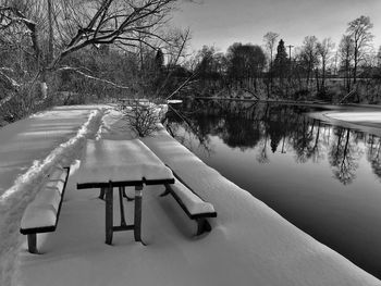 Empty bench by lake during winter