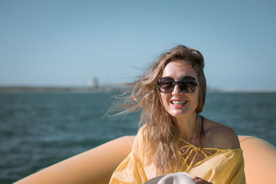 Portrait of smiling young woman sitting in boat on sea