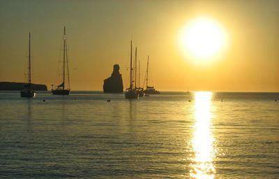 Sailboats sailing in sea against clear sky during sunset