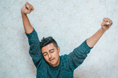 Portrait of young man lying down against wall