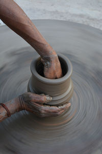 Hands working on pottery wheel and making a pot