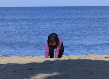 A girl is playing in the sand on the beach against the sea background