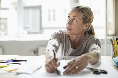 Businesswoman drawing line using ruler on paper while looking away