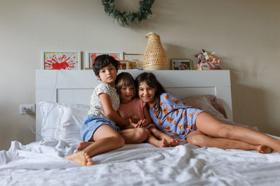 Group of smiling children laying in parent's bed posing for photo