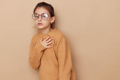 Portrait of cute girl wearing sweater against beige background