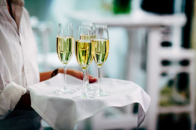 Midsection of waiter carrying champagne at restaurant