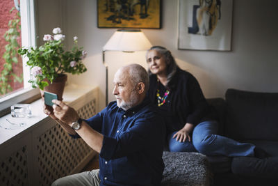 Senior man taking selfie with woman through mobile phone at home