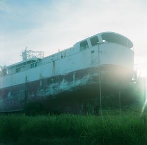 Low angle view of abandoned bus on field against sky