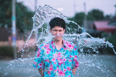 Man standing amidst splashing water