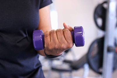 Close-up of senior black woman lifting dumbbell in gym for health and fitness.