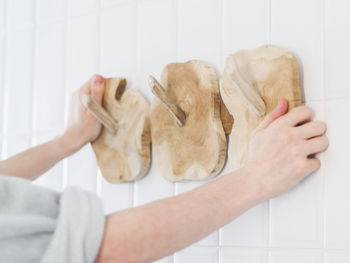 The hands of a young caucasian guy hangs a new wooden stylish and eco-friendly hanger on the wall