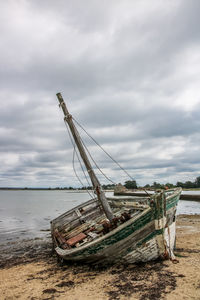 Abandoned ship moored on shore against sky