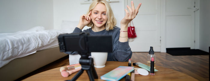 Young woman using mobile phone while sitting on table