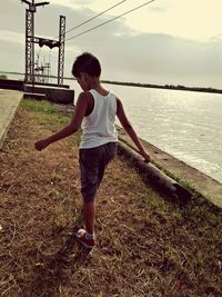 Full length of boy on grass at sea shore