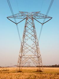 Low angle view of electricity pylon on land against clear sky