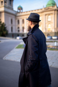 Side view of man standing on street against building