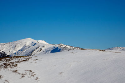 Scenic view of snowcapped mountains against clear blue sky