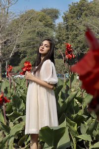 Portrait of young woman standing amidst plants