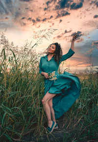 Full length of woman standing on field against sky during sunset