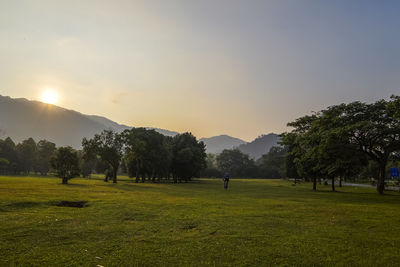 Mid distance view of man riding bicycle on land against sky during sunset