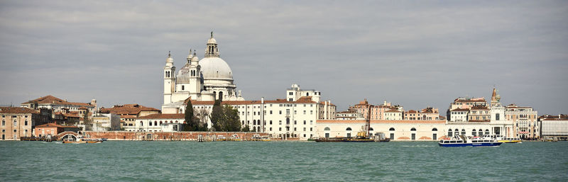 View of buildings by canal against sky