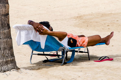 Low section of men lying on beach