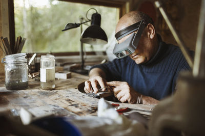 Senior craftsman working at table in workshop