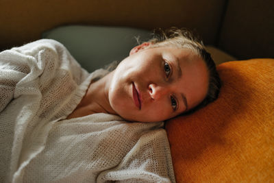 Portrait of young woman lying on sofa at home