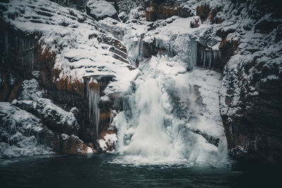 Scenic view of frozen waterfall by lake