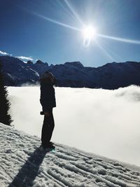 Silhouette mid adult woman standing on snow covered mountain against sky during sunny day