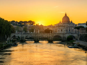 Arch bridge over river during sunset