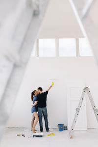 A young couple in love have moved into a new house and are making repairs painting white walls