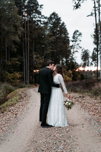 Full length of couple standing by tree