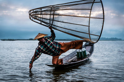 Man fishing in sea against sky