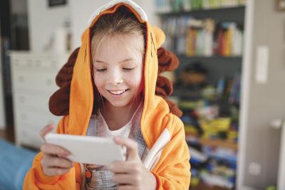 Smiling girl playing on mobile phone at home