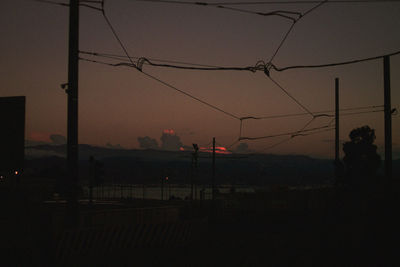 Silhouette electricity pylon against sky at sunset