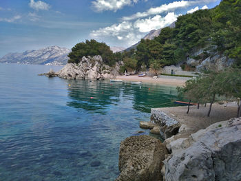 Scenic view of sea by mountain against sky