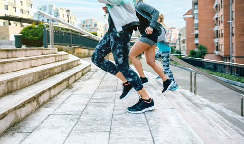 Young women friends training running up stairs in town