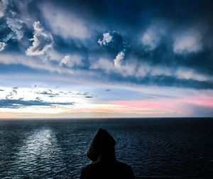 Silhouette man looking at sea against sky during sunset